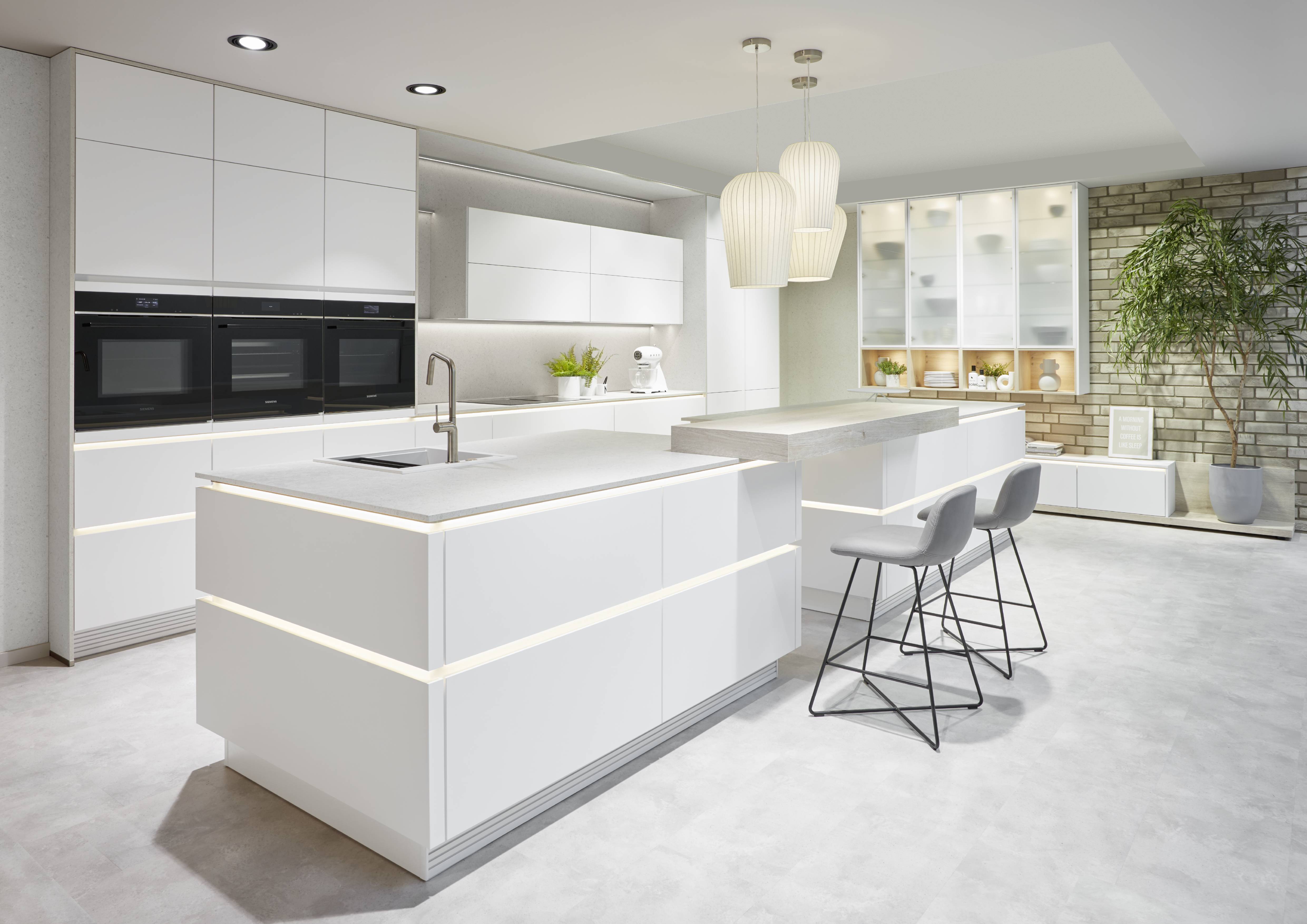 Modern white kitchen remodel with island and seating Modern white kitchen with a large island, integrated lighting lines, bar seating, and a bright minimalist layout