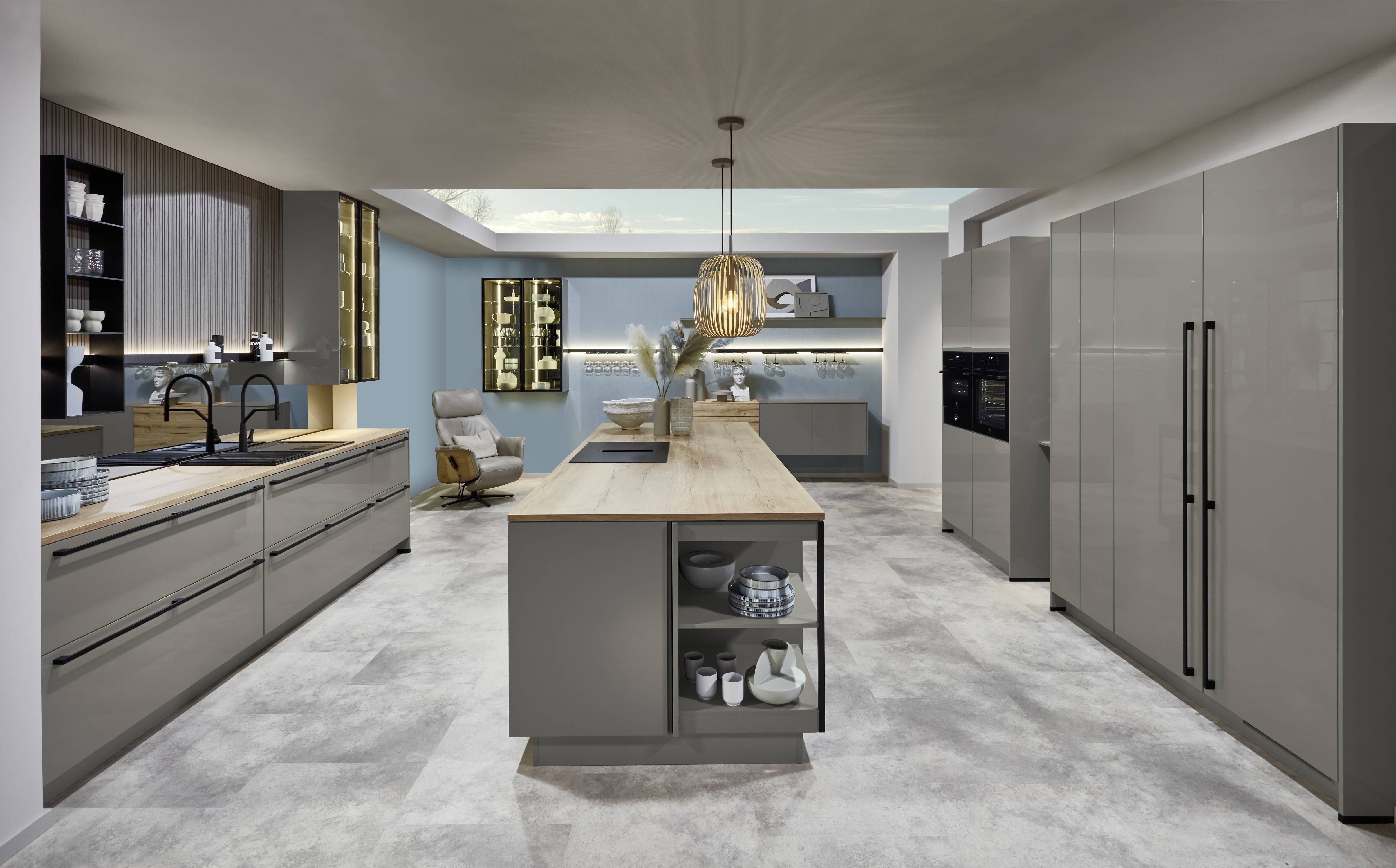Contemporary kitchen with a long wood island, integrated sink, and open shelving detail in a spacious modern layout