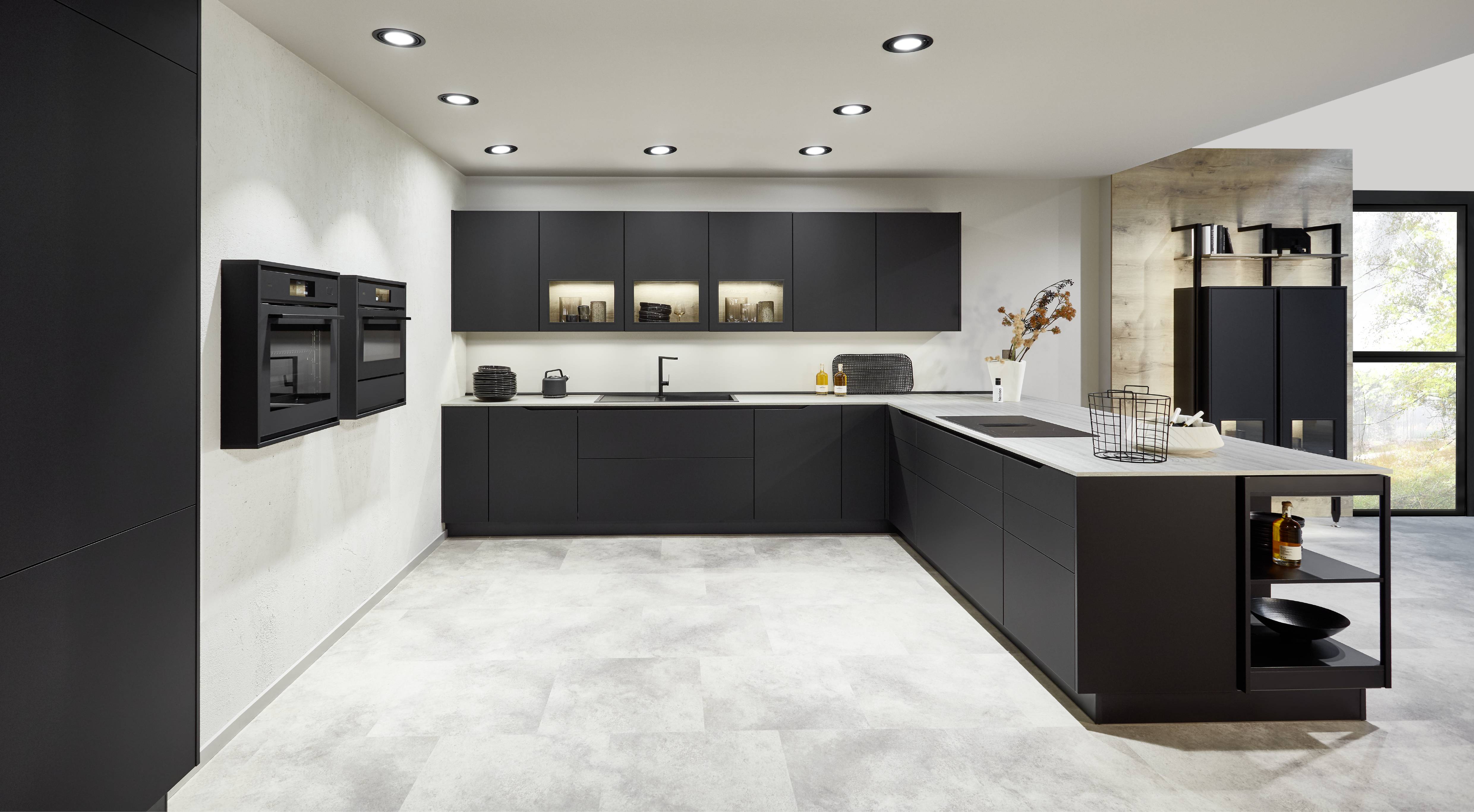 Matte black, handleless L-shaped modern kitchen with built-in wall ovens, recessed lighting, and a waterfall island with open shelving. Matte Black Modern L-Shaped Kitchen with Waterfall Island