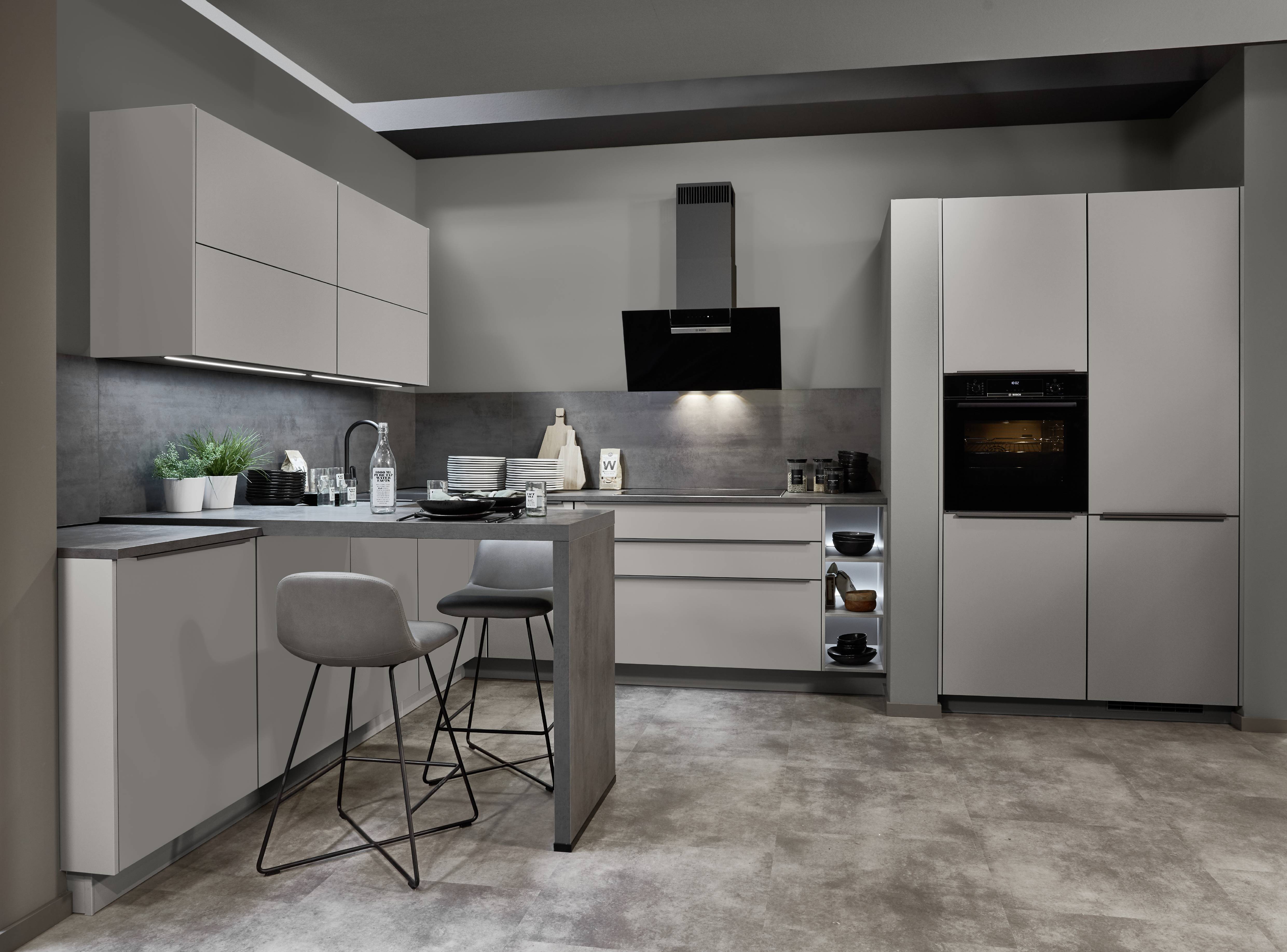 Modern grey kitchen with peninsula seating Modern grey kitchen with a compact peninsula, integrated appliances, and a dark backsplash in a streamlined layout