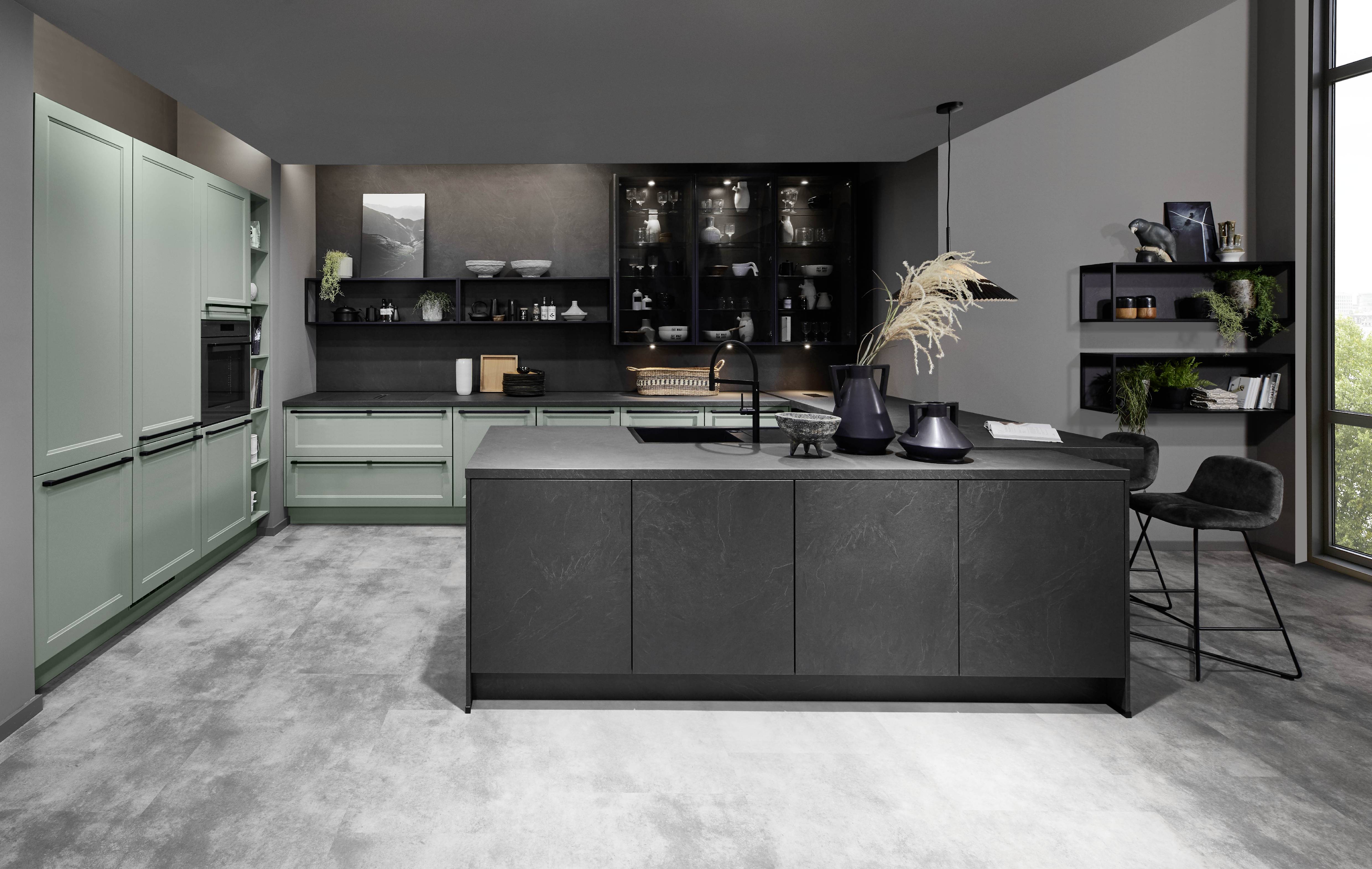 Modern luxury kitchen with muted green cabinetry and a dark island, creating a dramatic and refined look