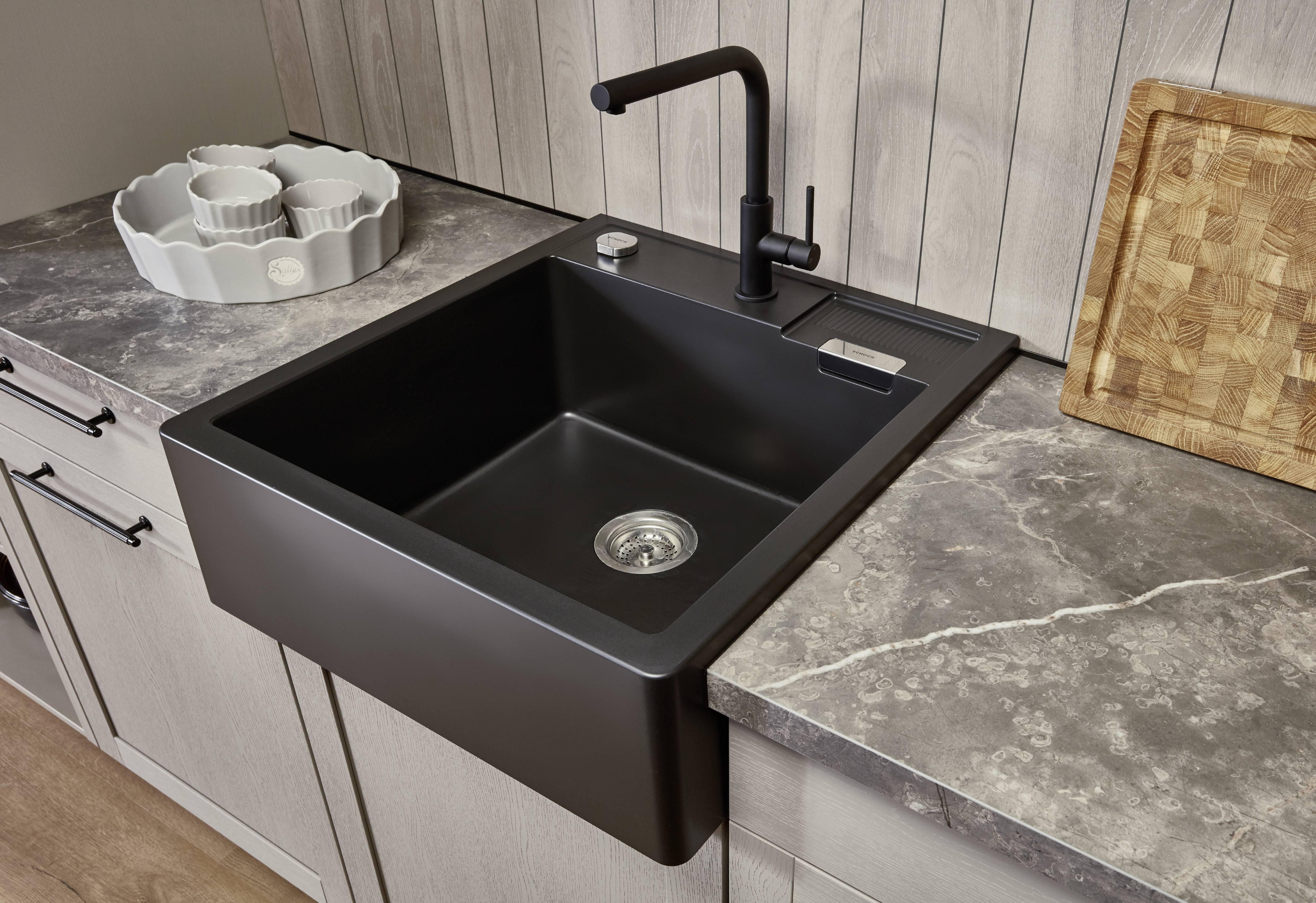 Matte black kitchen faucet and apron-front sink Matte black kitchen faucet with a deep apron-front sink on a gray stone-look countertop