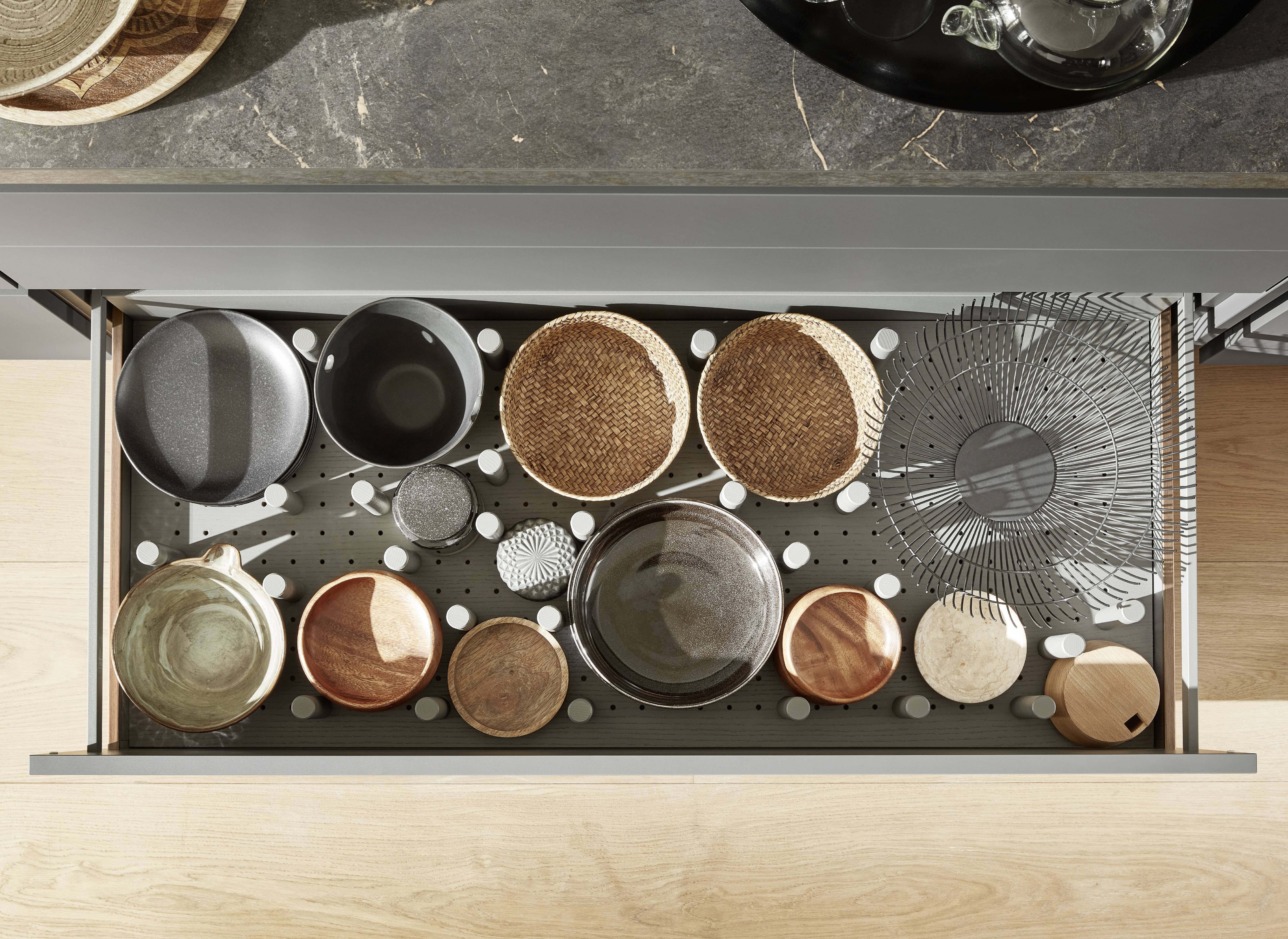 A deep kitchen drawer with adjustable peg organizers keeps cookware, bowls, and tools neatly separated and easy to access.