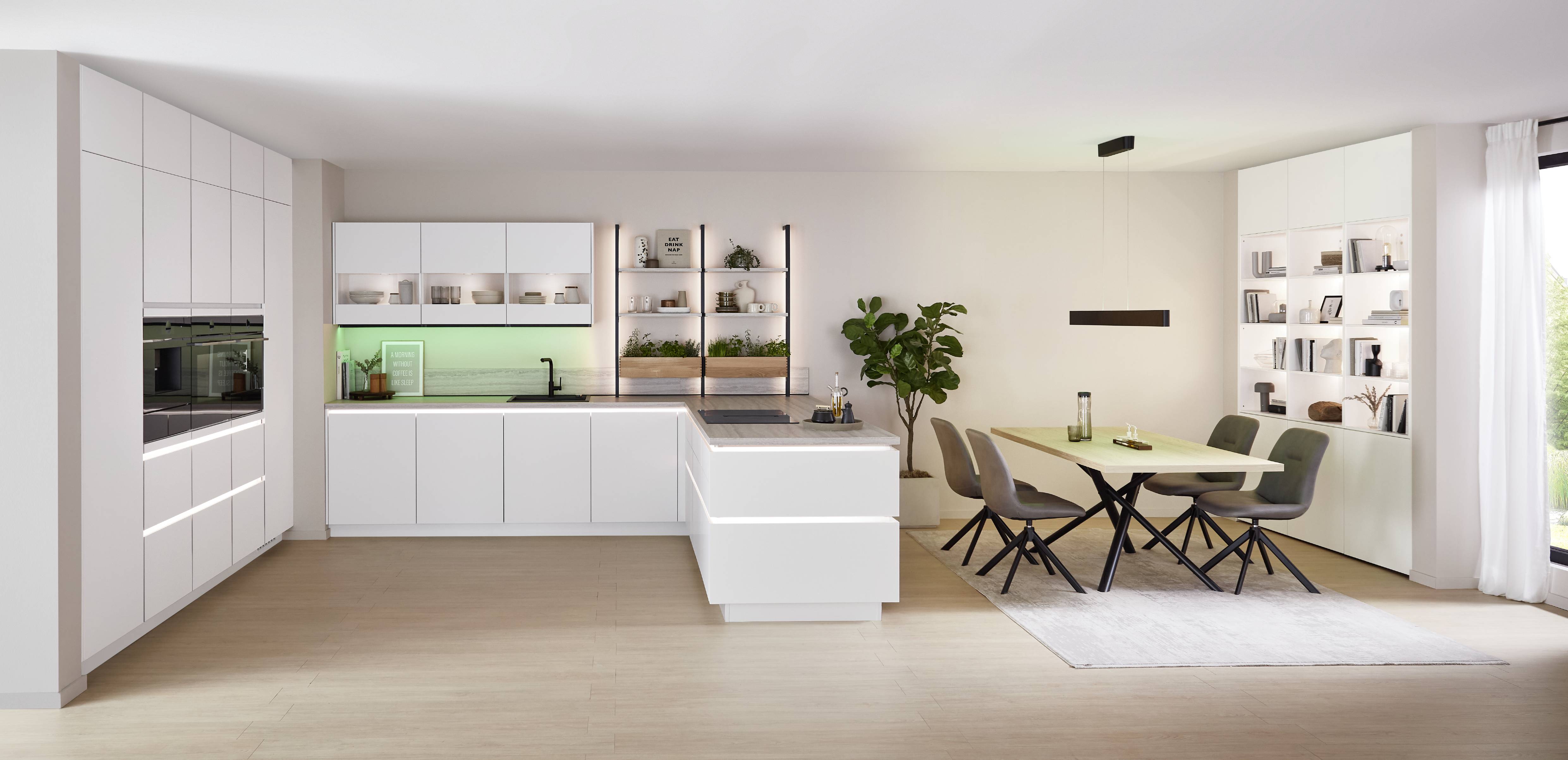 noblessa USA - Modern White Kitchen with Soft Green Accent Lighting Bright contemporary white kitchen with sleek cabinetry, a central island, open shelving with plants and dishware, and a dining area illuminated by soft green accent lighting.