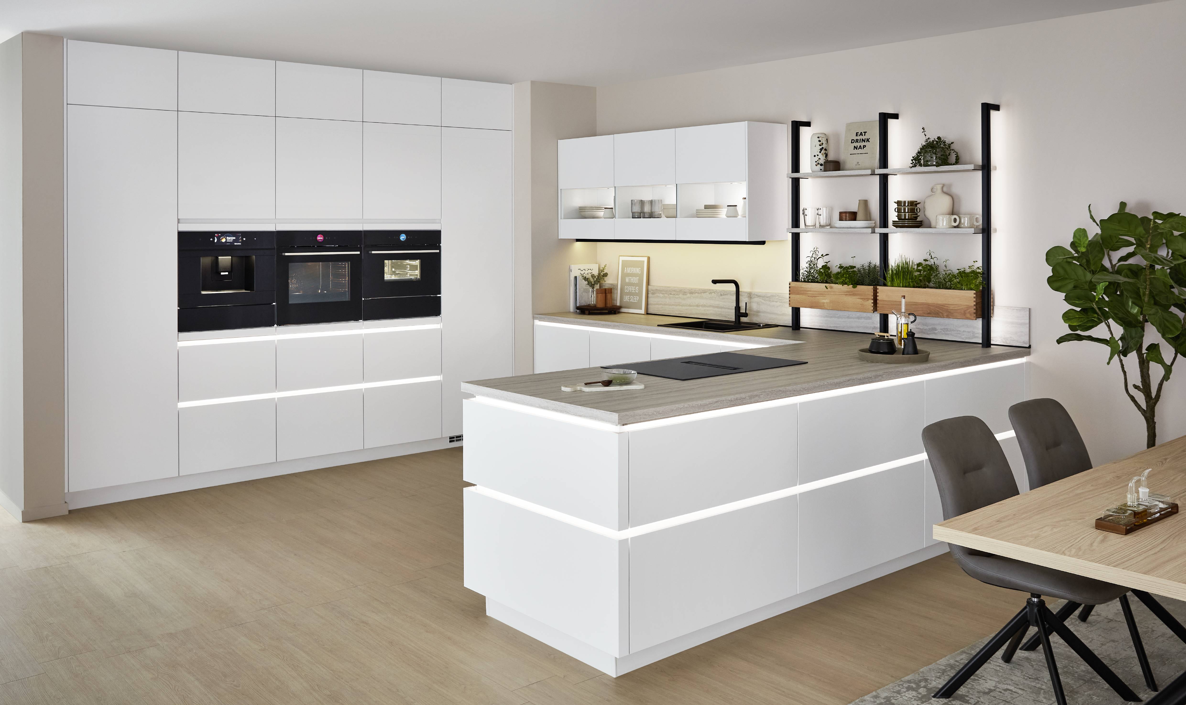 Minimalist white kitchen with an island, integrated wall cabinetry, and a calm neutral palette