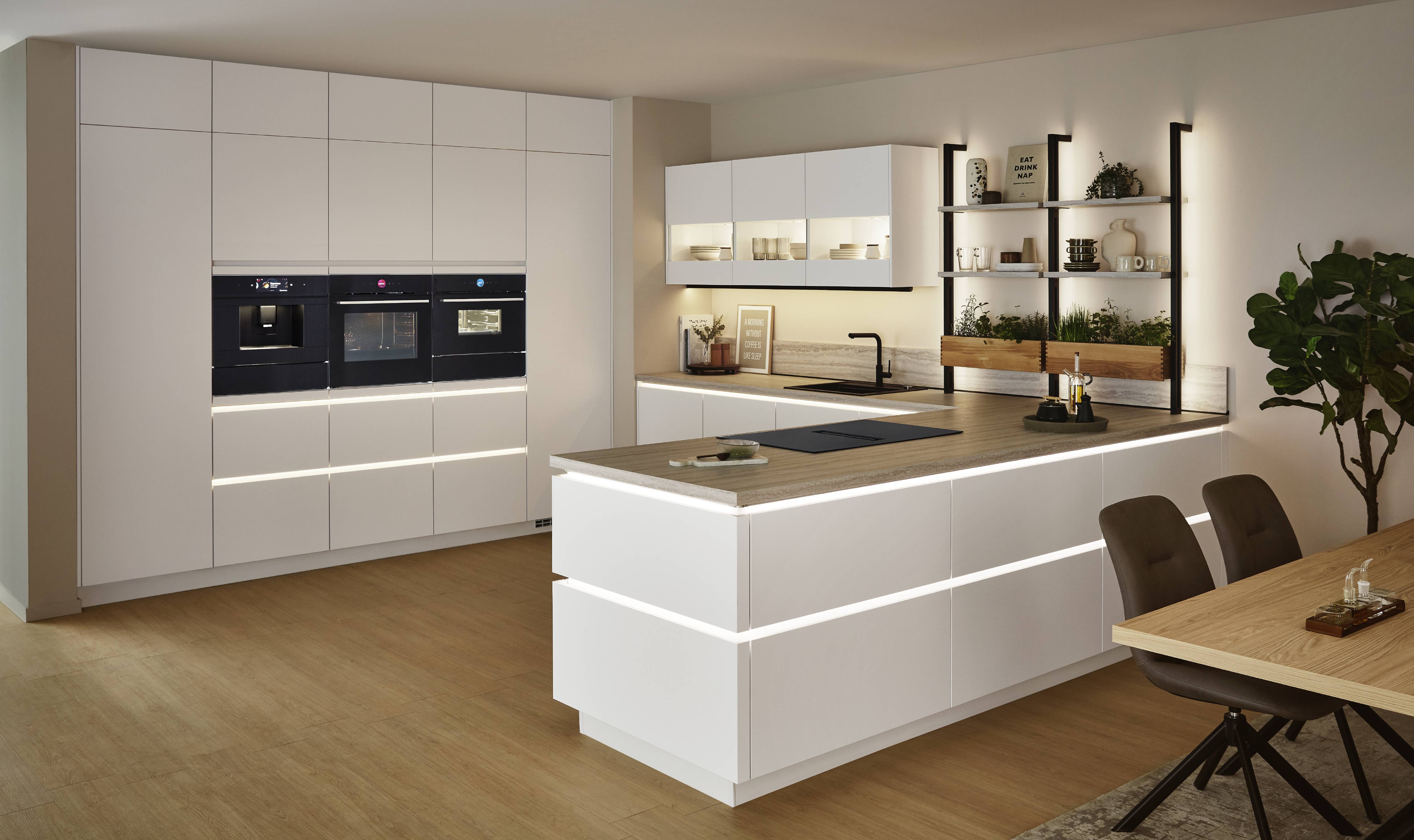 Bright modern kitchen with a large island and layered lighting that highlights the cabinetry and work surfaces