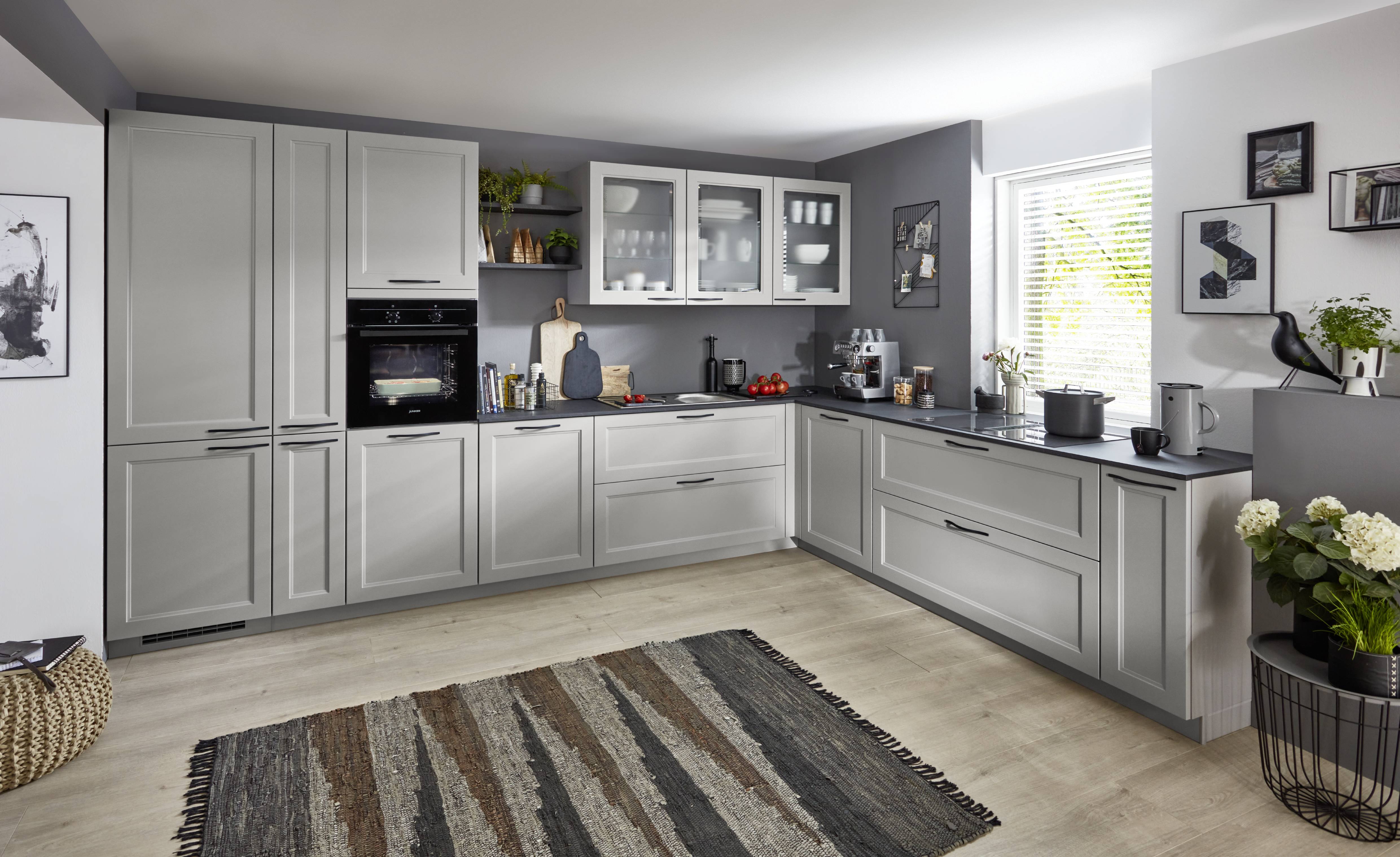 Grey L-shaped kitchen with clean cabinetry, a large window, and a simple layout designed for daily use