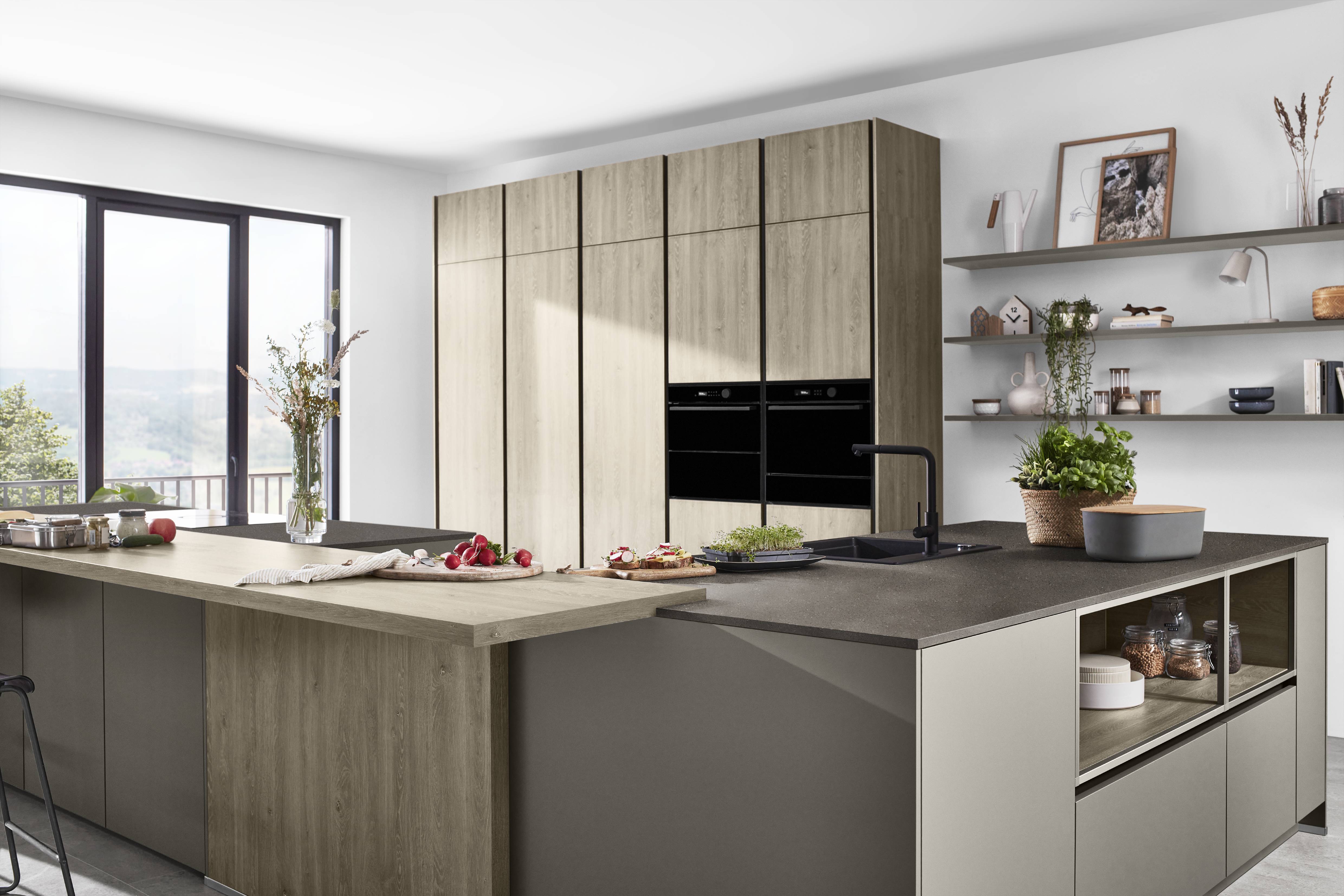 noblessa USA - Modern German Kitchen with Natural Wood Cabinetry and Dark Countertops Modern German kitchen featuring natural wood cabinetry, dark countertops, integrated black appliances, a spacious island, open shelving, and a large window providing natural light.