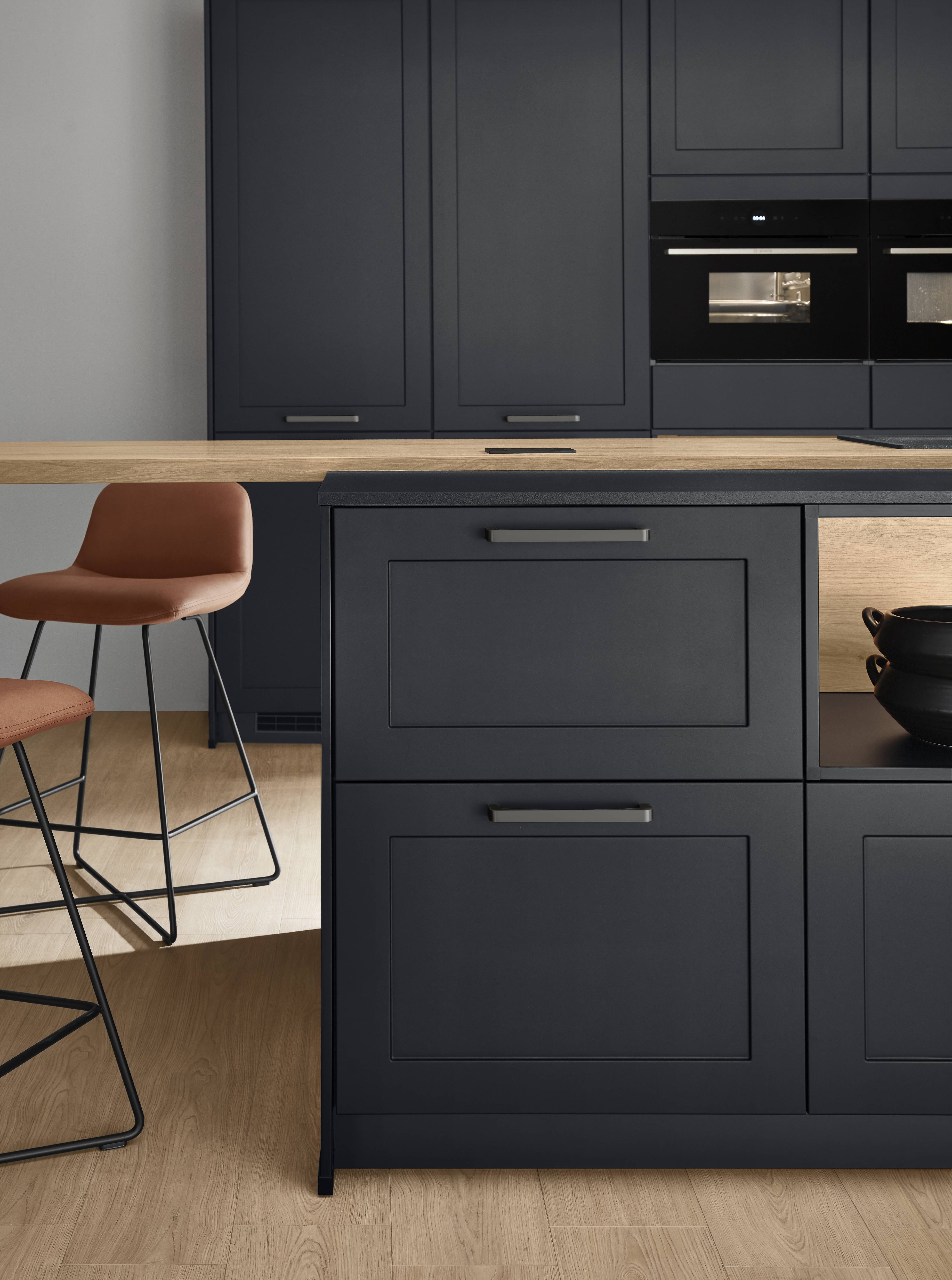 Deep navy kitchen cabinets with a warm wood counter and a modern island detail in a minimalist kitchen
