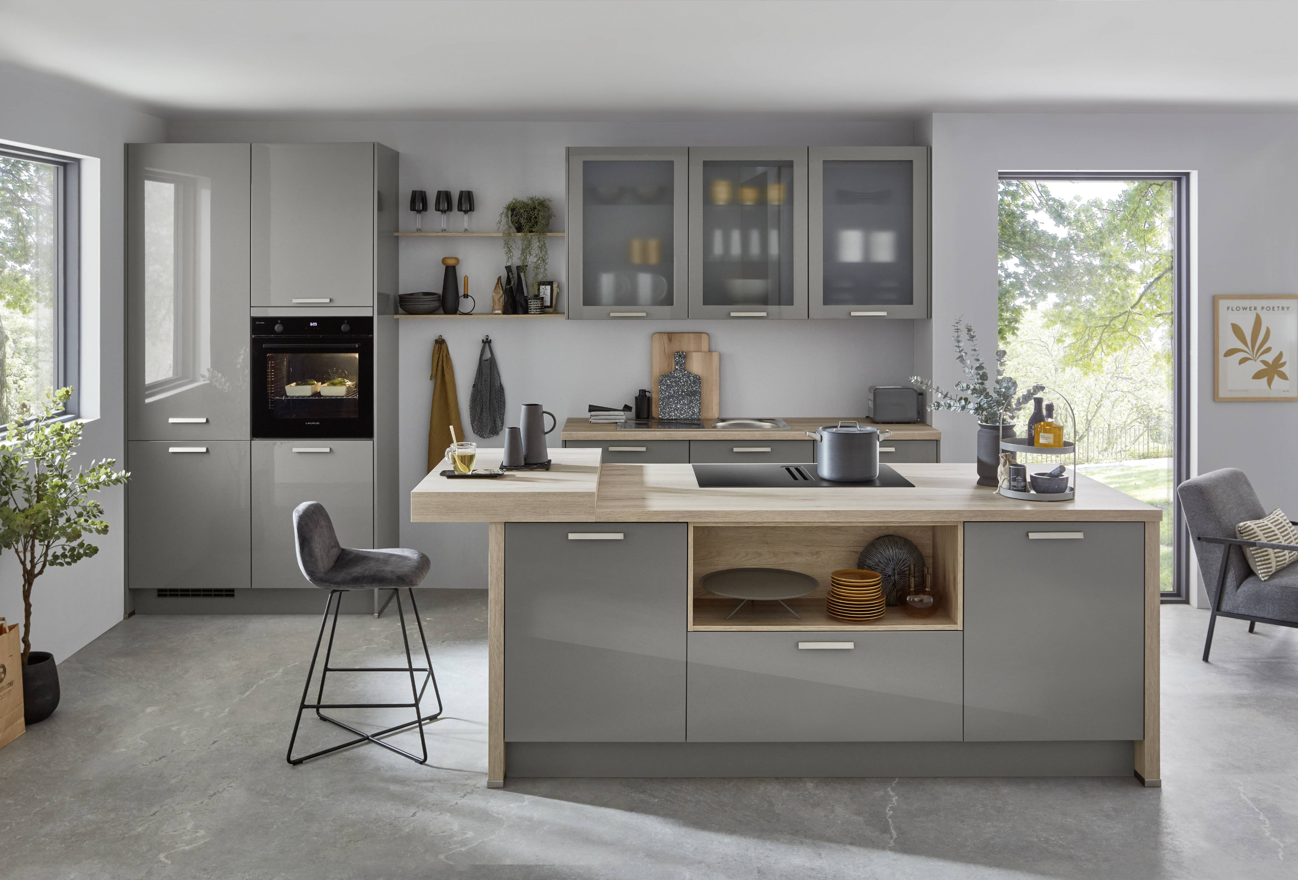 A sophisticated compact German kitchen featuring sleek gray cabinetry, integrated appliances, a multifunctional island, warm wood accents, and abundant natural light.