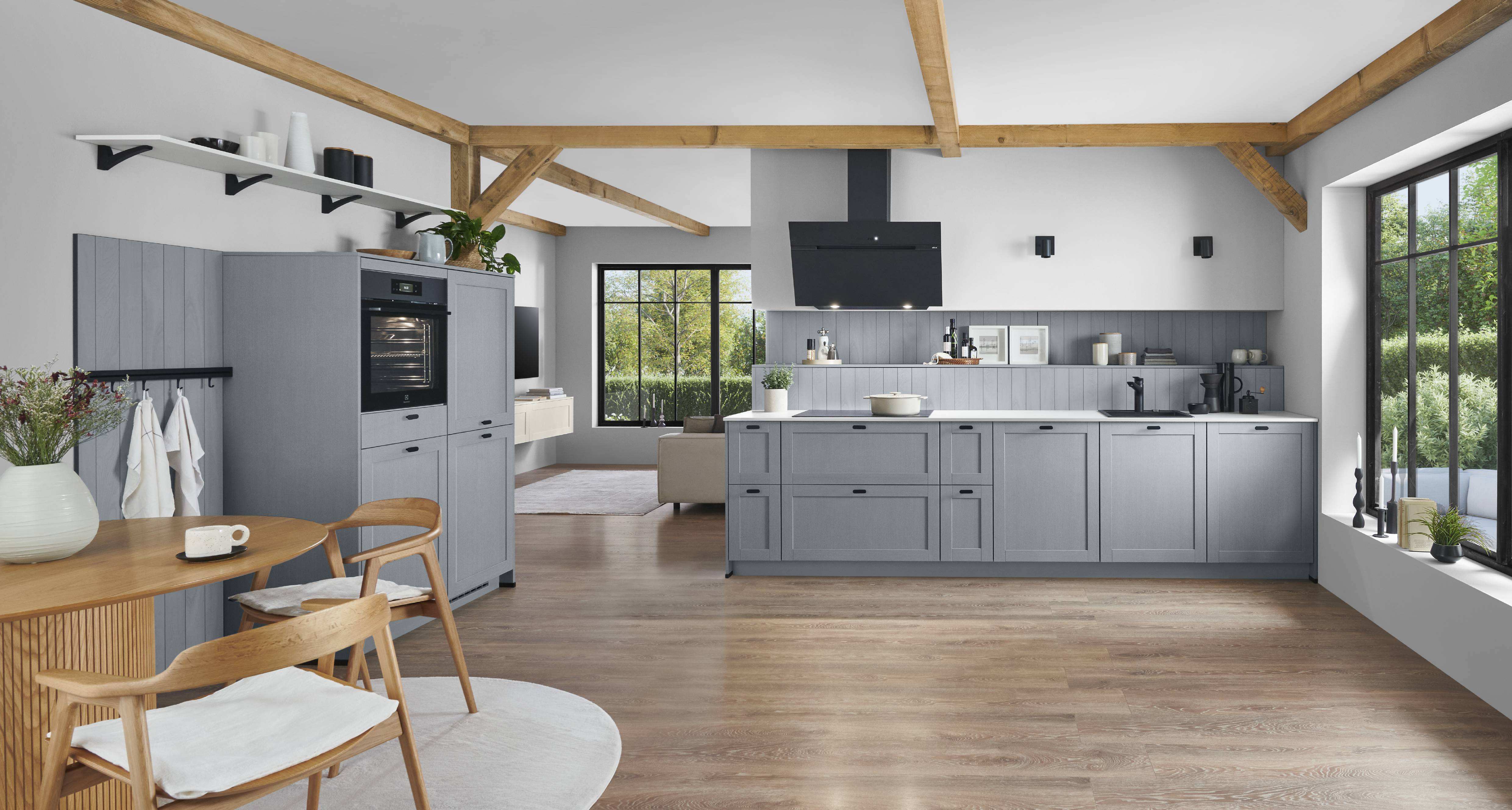 A warm and inviting German kitchen featuring refined gray cabinetry, natural wood accents, open shelving, and expansive windows that bring the beauty of the outdoors into the space.