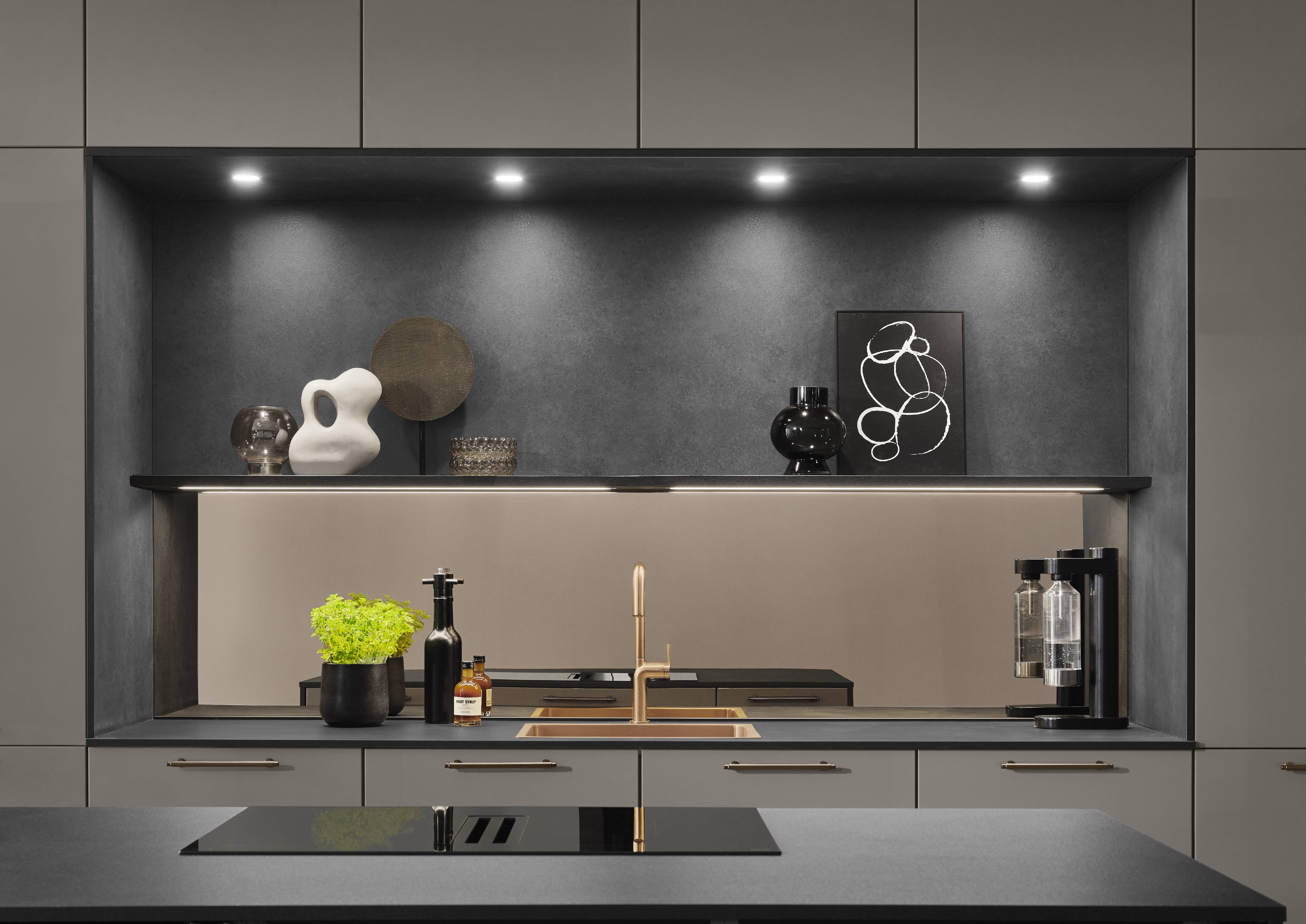 A sleek noblessa kitchen vignette showcasing refined European cabinetry, an illuminated backsplash niche, and integrated lighting for a more luxurious, functional workspace.