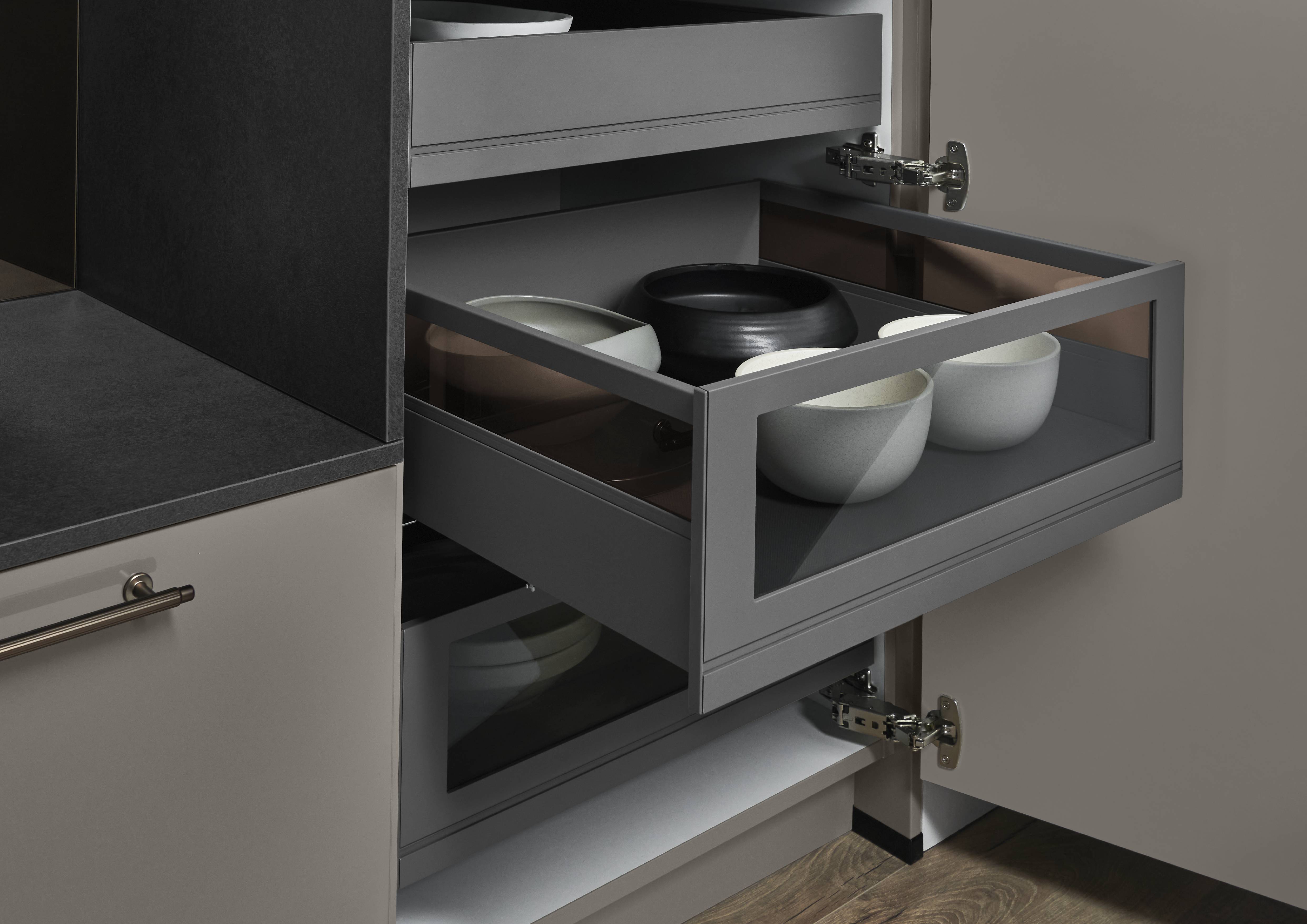 Close up cabinet drawer detail with clean lines and refined styling Close up of a modern cabinet drawer with glass sided storage and neutral dishware, showing clean lines and refined design
