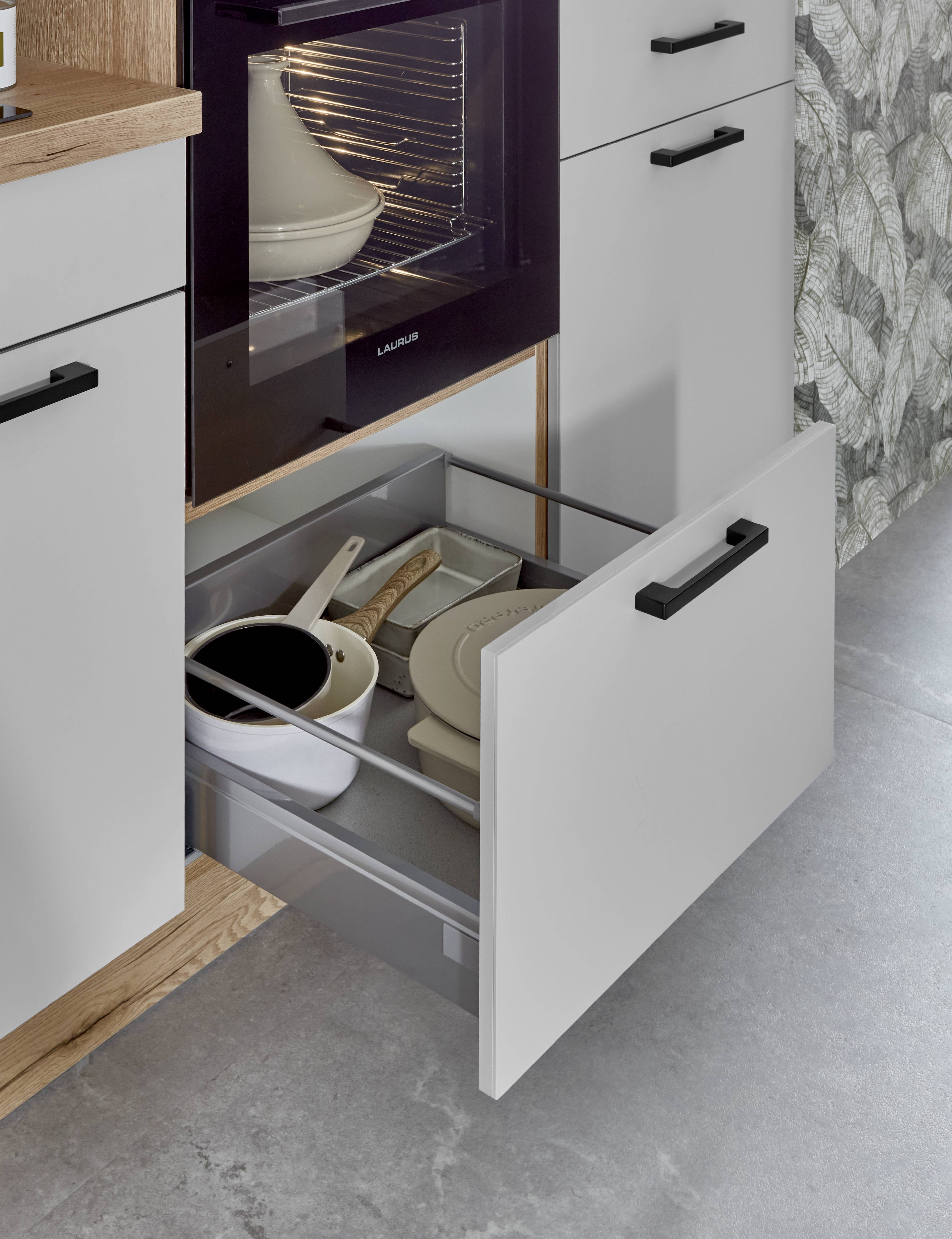 Noblessa USA - Modern Kitchen Pull-Out Storage Drawer Beneath Built-In Oven White pull-out kitchen storage drawer beneath a built-in oven, containing cookware, trays, plates, and utensils in an organized modern cabinet setup.