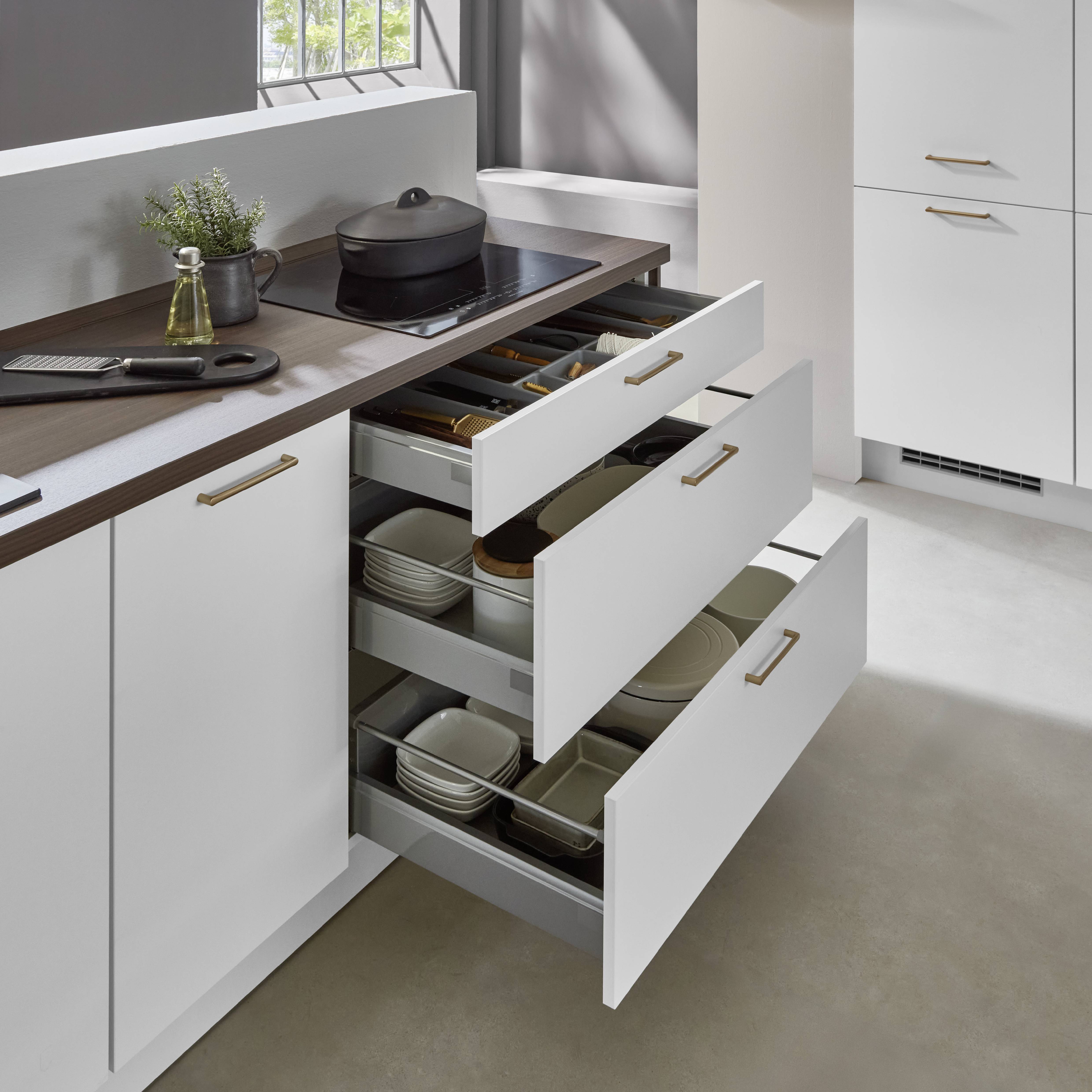 Modern compact kitchen design featuring sleek white cabinetry, deep pull-out storage drawers, and a warm wood countertop for a clean and functional space.