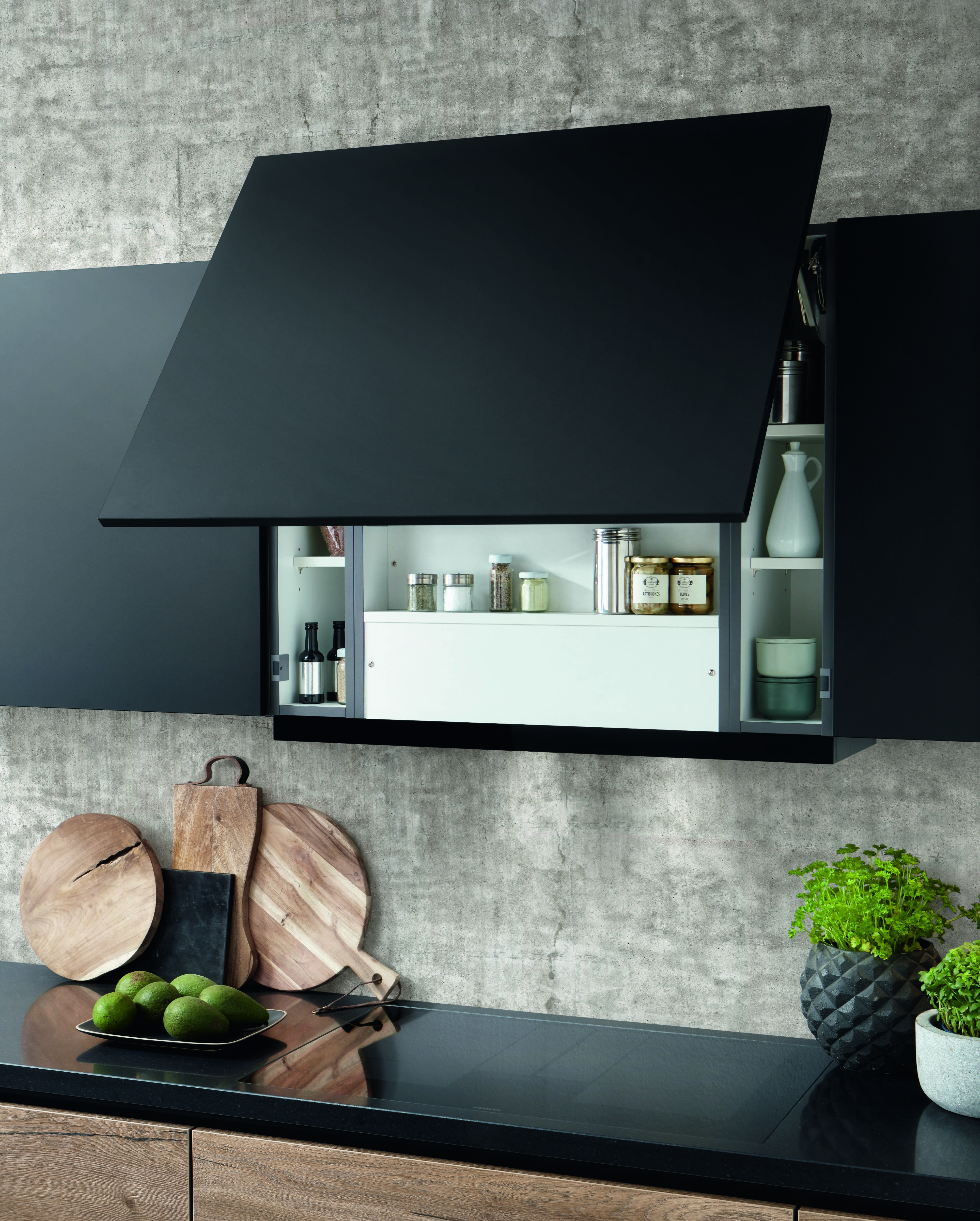 A matte-black lift-up cabinet door reveals streamlined storage - an industrial-style detail that keeps the kitchen clean and functional.