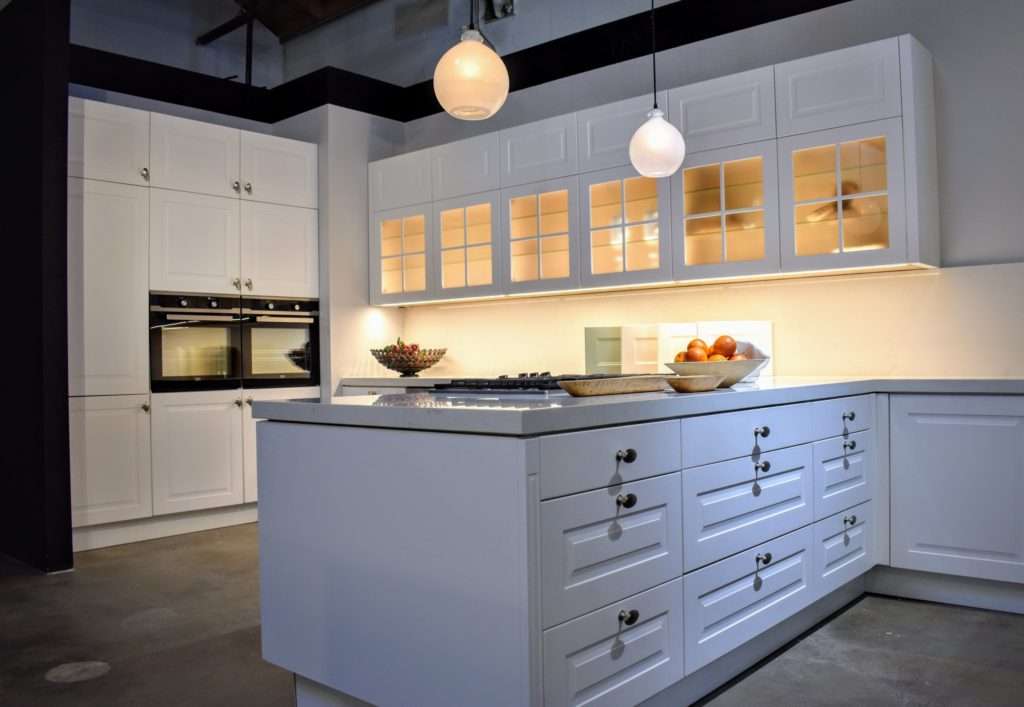 Tempo Collection kitchen display in white. Noblessa Pasadena kitchen showroom display with soft dim lighting.