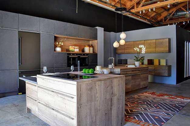 Pasadena kitchen showroom display. Island counter with natural wood finish and inset flat stovetop.