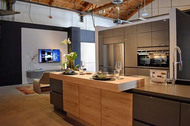 Pasadena kitchen showroom display. Image features a wraparound counter with glossy grey finish and light wood elevated breakfast bar.